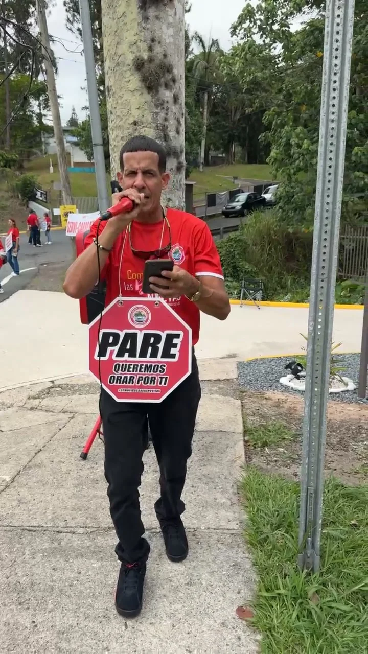 Miembro de la iglesia sosteniendo un letrero que dice Pare, queremos orar por ti